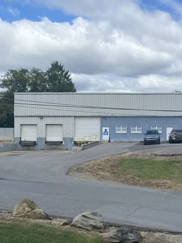 Industrial warehouse facility with multiple loading docks and commercial vehicles for food distribution and supply chain logistics.