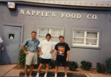 Three team members standing outside Nappie's Food Co. warehouse, representing foodservice distribution and supply chain operations.